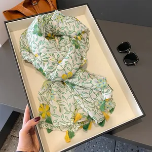 Sciarpa in cotone e lino a fiori con motivi di rami verdi e nappe su un vassoio