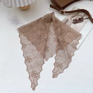 Detailed view of a brown floral lace headscarf with scalloped edges on a lifestyle background