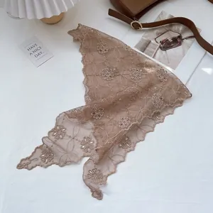 Detailed embroidery of cream floral lace headscarf on a cozy flat lay setting