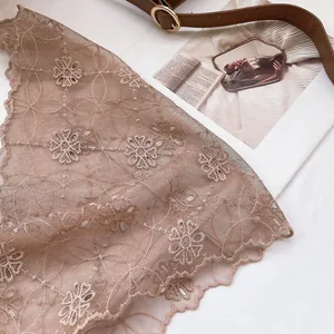 Detailed close-up of cream lace headscarf featuring floral embroidery and wavy edges
