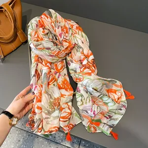 Linen feel floral scarf with tulip print and orange tassels on a dark grey surface