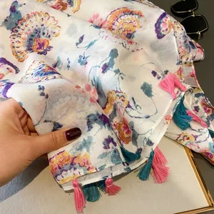 Détail de l'écharpe en coton et lin avec imprimé floral et franges à pompons colorés