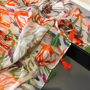 Detailed view of lightweight tulip print scarf featuring orange tassels and cotton linen texture