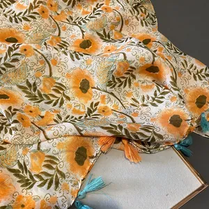 Detail of floral print scarf featuring orange blossoms and two-tone tassel edges