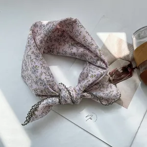 Detail of pink floral cotton linen scarf with green crochet lace edges on a magazine