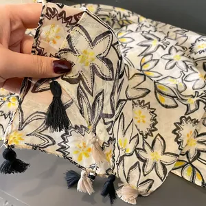 Détail d'une écharpe fleurie montrant la texture légère et les bords à franges