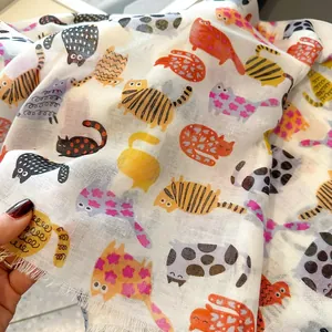 Detail of soft cotton-linen scarf with colorful cartoon cats and fringe edges