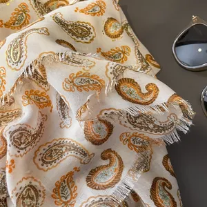 Sciarpa beige in cotone e lino con motivo paisley dorato e bordi sfrangiati moda