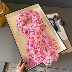 Dettaglio della sciarpa rosa paisley con nappe piegata ordinatamente in un vassoio bianco
