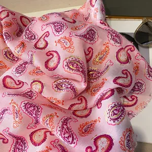 Dettaglio di sciarpa paisley rosa con bordi dorati metallici e frange morbide