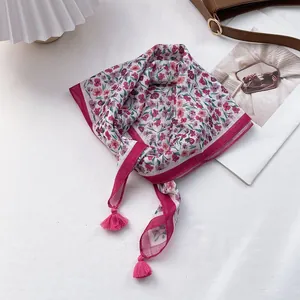 Detail view of the floral scarf corner featuring pink tassels and a decorative border