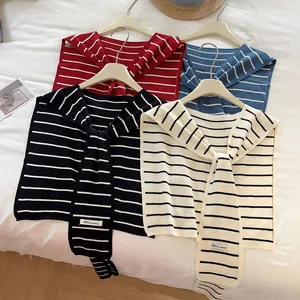 Cols de châle en tricot à rayures noirs, rouges et bleus sur cintres blancs