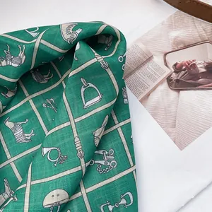 Close-up of green cotton scarf with vintage equestrian horse and buckle patterns