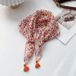 Detailed view of floral cotton linen scarf with bright orange tassel accents