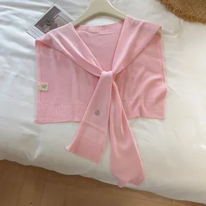 Detail of pink knitted shawl collar with sailor design and metal button tie