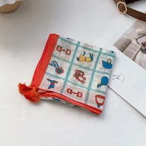 Detail shot of a square cotton scarf with horse motif patterns and orange corner tassels