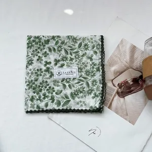 Detail of floral cotton handkerchief with dark green crochet lace edges on a white background