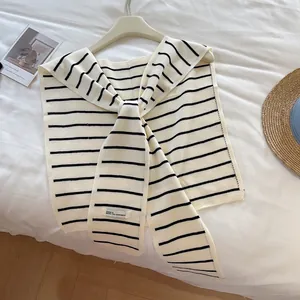 Châle en tricot à rayures noires et blanches avec nœud frontal sur un fond blanc doux