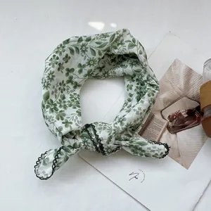 Detailed view of floral cotton linen scarf with green scalloped edges on white magazine