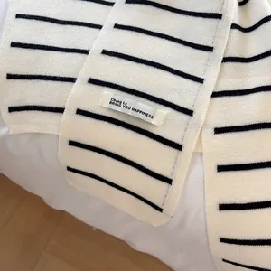 Détail d'un châle en tricot à rayures noires et blanches avec texture et étiquette logo