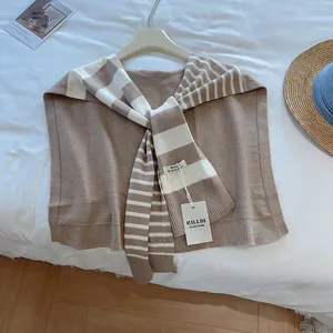 Detail eines braun-cremefarbenen gestreiften Strickschals an einem Kleiderbügel