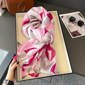 Pink and grey geometric print lightweight scarf with tassels on a display tray