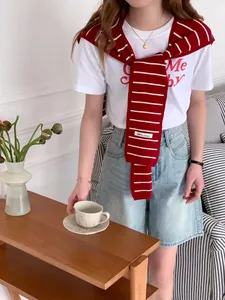 Détail d'un châle en tricot rayé rouge et blanc sur un t-shirt blanc et un short en jean