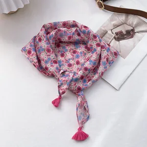 Detail of pink floral square scarf featuring delicate tassels and soft cotton-linen fabric