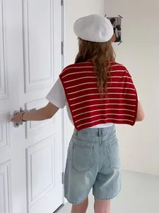 Détail d'un châle en tricot rayé rouge et blanc superposé sur un T-shirt blanc