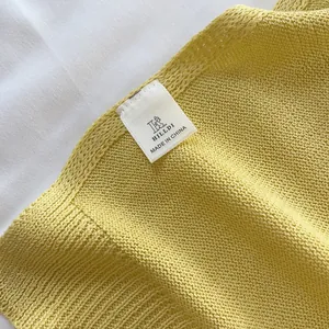 Detail of yellow knit fabric texture and brand label showing quality craftsmanship