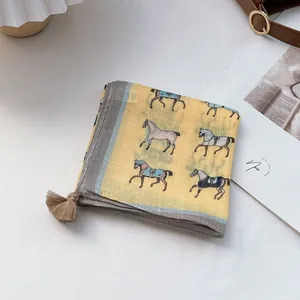 Detail of yellow cotton scarf with horse pattern, grey borders and brown tassels