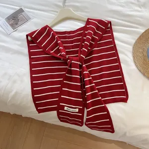 Détail du châle en tricot rayé rouge et blanc avec liens et petite étiquette tissée