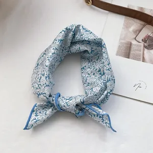 Close-up of blue floral silk scarf tied elegantly with delicate stitched edges
