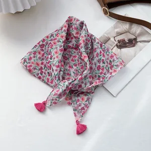 Detail of floral printed cotton linen scarf with elegant pink tassel charms on edges