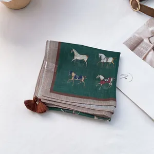 Detailed view of dark green scarf featuring equestrian horse print and corner tassels