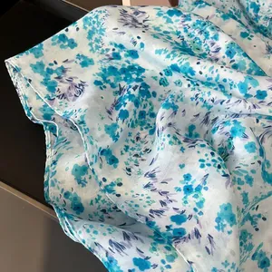 Close-up of lightweight floral silk scarf with elegant blue flower patterns and soft sheen