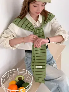 Détail d'un châle en tricot à rayures vertes porté sur une chemise blanche élégante