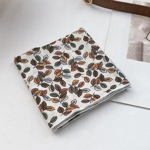 Détail du foulard en coton à imprimé feuilles d'automne avec finition roulottée fine