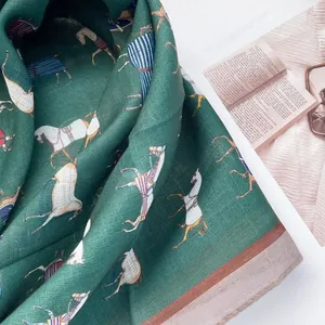 Close-up detail of dark green cotton scarf featuring elegant horse print and contrast border