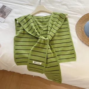 Détail du châle en maille à rayures vertes et brunes avec nœud en tissu texturé doux
