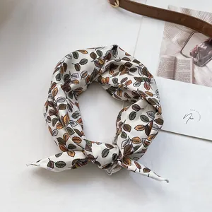 Détail d'un foulard en coton à motif floral et feuilles sur fond blanc pur