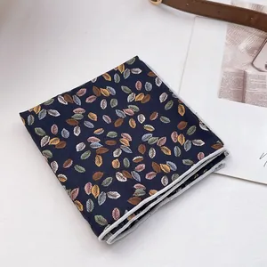 Détail d'un foulard en coton bleu marine avec imprimé floral coloré et bords ourlés