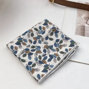 Gros plan d'un foulard en coton à fleurs avec des motifs de feuilles bleues et brunes
