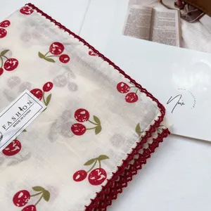 Detail of red cherry print fabric with delicate handmade crochet lace edging