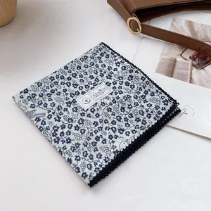Close-up of a floral cotton scarf featuring delicate blue lace edges and vine patterns