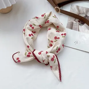 Detail of cream cotton linen scarf with cherry print and red crochet lace border