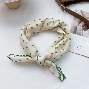 Close-up of cotton bandana with green polka dots and delicate crochet lace edging