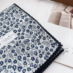 Detailed view of floral cotton scarf with blue crochet lace trim and product tag