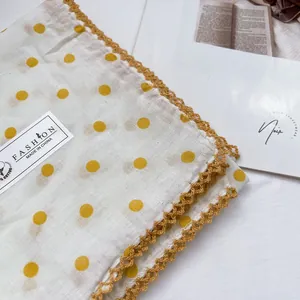 Detail view of cotton bandana with yellow polka dots and golden crochet lace edges
