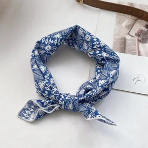 Détail d'un foulard en coton imprimé bleu et blanc noué comme accessoire de coiffure